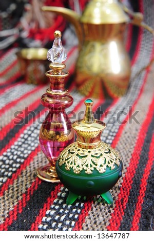Egyptian perfume bottles arranged on a hand-woven Omani rug.  A copper replica of a traditional coffee pot and small cup is faded in the background.