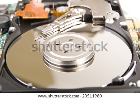 A close up inside of a hard disk drive, showing the disk surface and drive head. Some IC\'s are also visible.