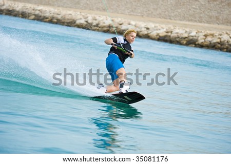 A wake-boarder enjoying the action of riding the wake of the boat.