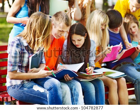 Group student with book on bench outdoor.