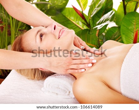 Woman getting facial massage in tropical beauty spa.