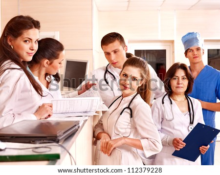 Group doctors and patient standing at reception in hospital.