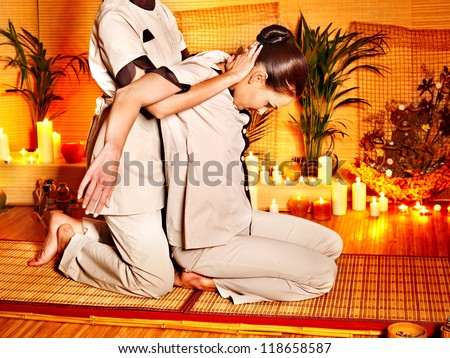 Therapist giving Thai stretching massage to woman.