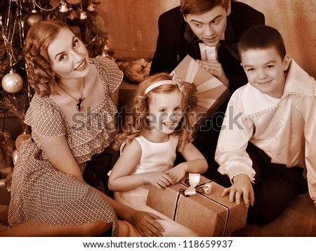 Happy family with children  receiving gifts under Christmas tree. Black and white retro.