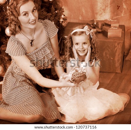 Child with mother receiving gifts under Christmas tree. Black and white retro.