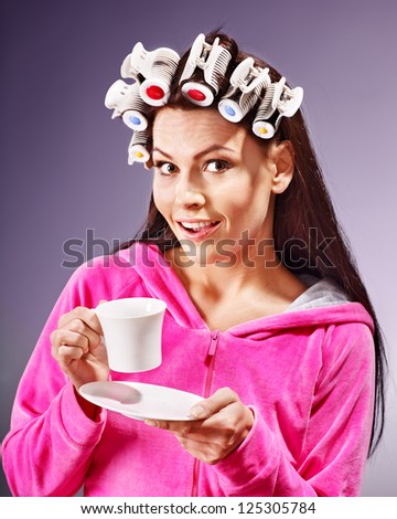 Woman wear hair curlers on head holding cup of coffee.