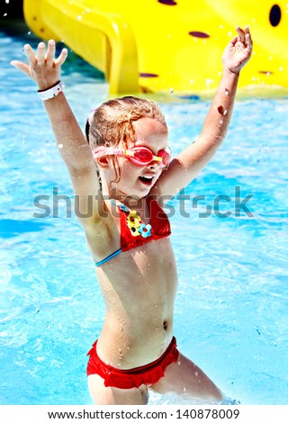 Child with armbands playing in swimming pool. Summer outdoor.