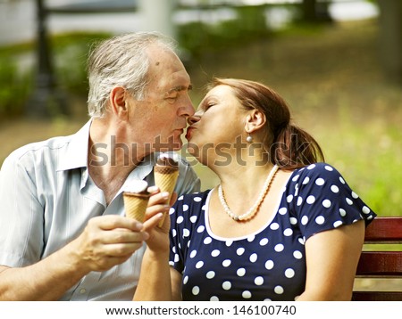 Kiss happy old couple eating ice-cream outdoor.