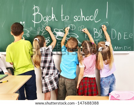 Children writing on blackboard at school.
