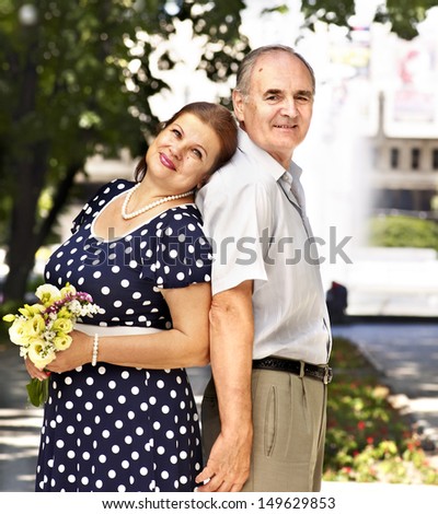 Happy old couple with flower back to backoutdoor.