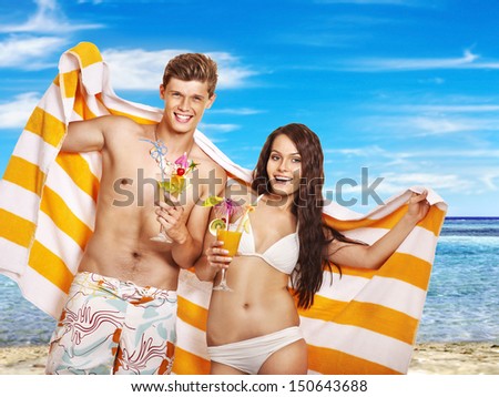 Couple with cocktail and towel at  beach. Summer outdoor.