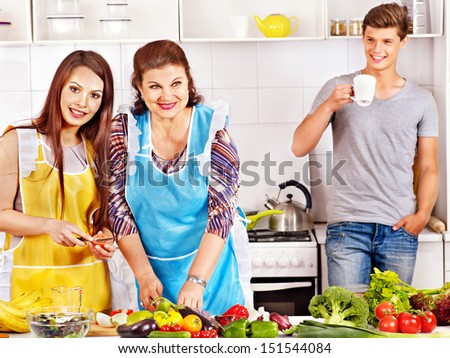 Mature woman with family preparing  dinner at kitchen.