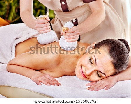 Woman getting herbal ball massage treatments  in spa.