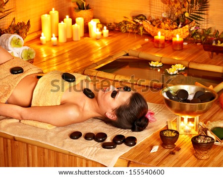 Woman getting stone therapy massage in bamboo spa.