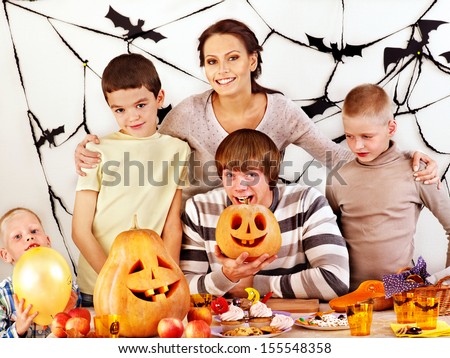 Family on Halloween party with children making carved pumpkin.