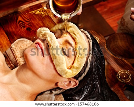 Woman having facial oil eyes mask at ayurveda spa.