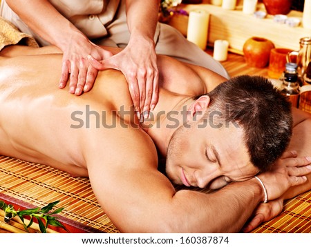 Man getting massage in bamboo spa. Female therapist.