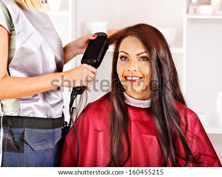 Woman at hairdresser with iron hair curler.