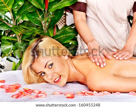 Blond woman getting massage in tropical spa.