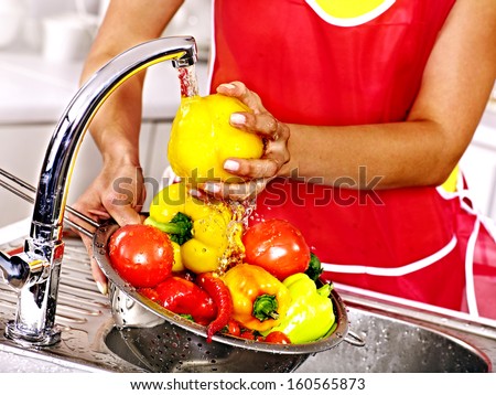 Happy woman washing fruit at kitchen.