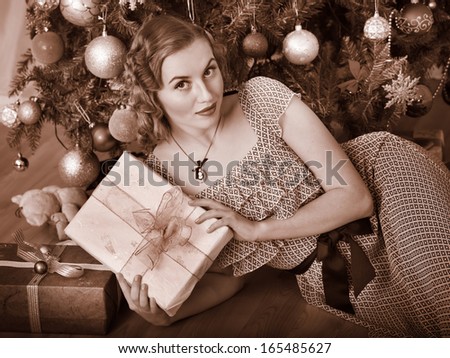Woman receiving gifts under Christmas tree. Black and white retro.