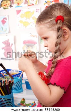 Little girl with colour pencil in play room.