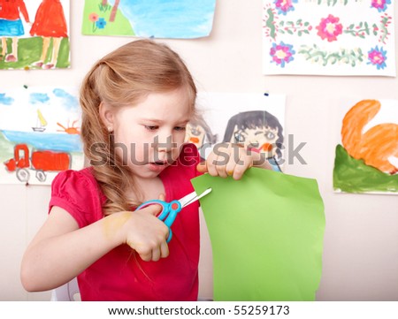 Little girl  with scissors cut paper at home.