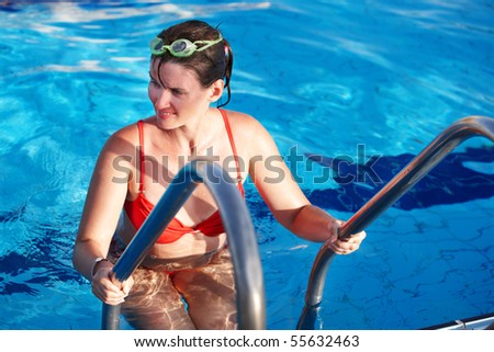 Young woman in sport goggles leaves swimming pool.
