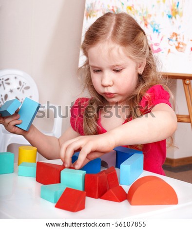 Child preschooler play wood block in play room.