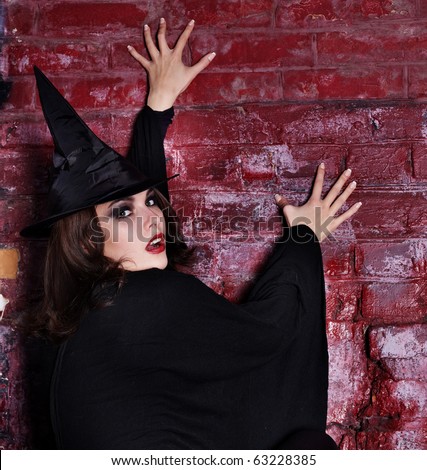 Brick wall portrait of young woman. Halloween witch.