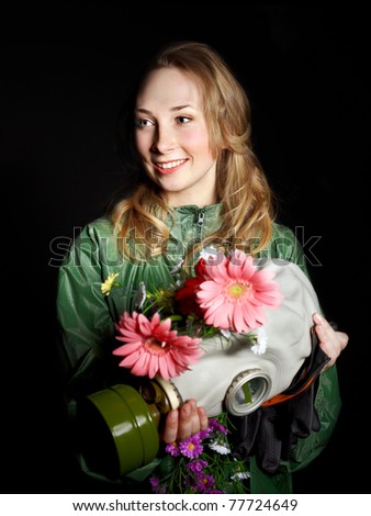 Young woman holding flowers and gas mask .