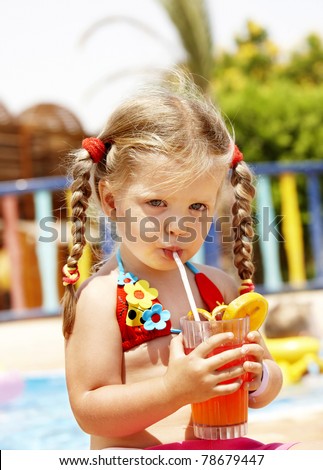 Child in  red bikini drinking through  straw  juice.