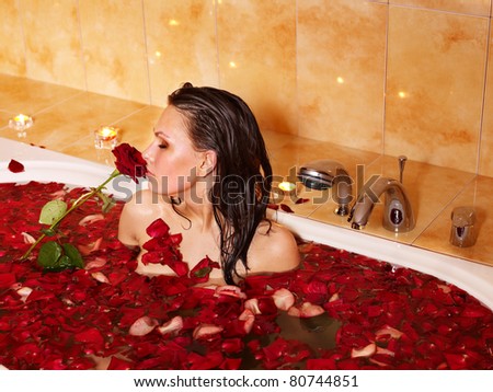 Woman relaxing in bath with rose petal.