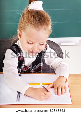 Happy schoolchild in classroom near blackboard.