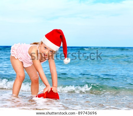 Child in Santa hat playing on  beach. Summer New Year.