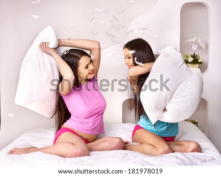 Two lesbian women at pillow fights in bed.