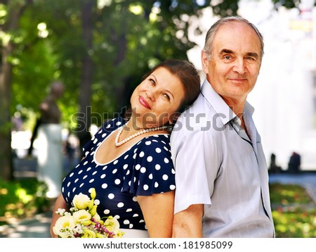 Happy old couple with flower back to back outdoor.
