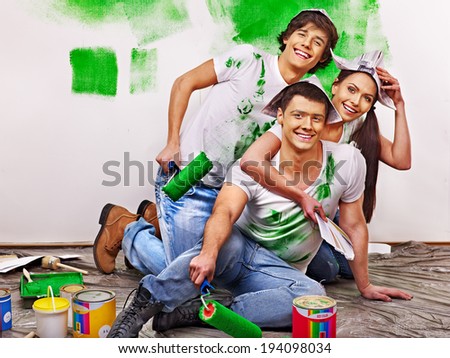Happy group people paint wall at home.