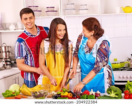 Mature woman with family preparing  dinner at kitchen.