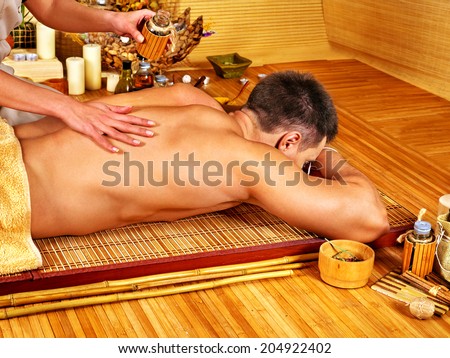 Man getting aroma massage in bamboo spa.