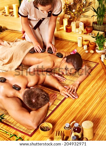 Woman and man getting stone therapy massage in bamboo spa.