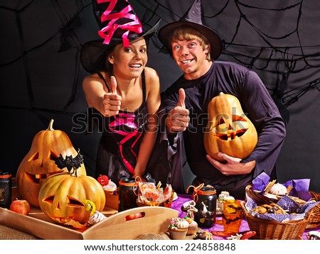 Man and woman on Halloween party  sitting at trick or treat table.