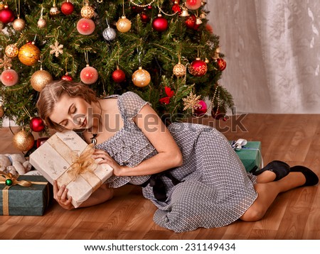 Happy woman receiving gifts under Christmas tree.