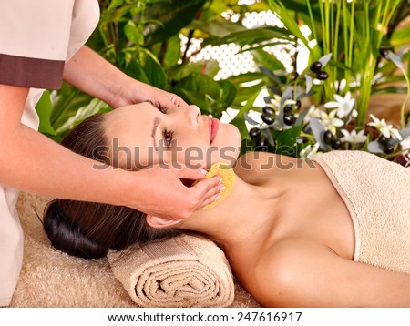 Woman getting facial massage in tropical beauty spa. Many live plants