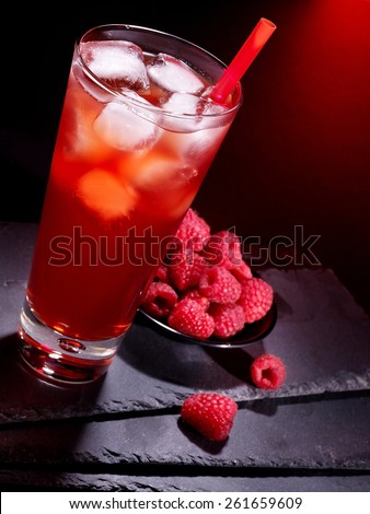 Red raspberry drink  with ice cube on black background.