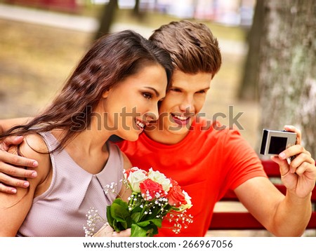 Couple with camera take pictures on bench. Selfie outdoor.