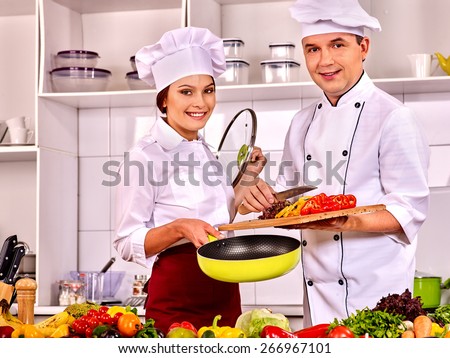 Happy man and woman professional in chef hat cooking chicken.