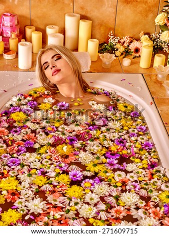 Woman relaxing at water spa. Aqueous surface covers a lot of colored flower heads.