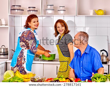 family of three people cooking at kitchen. Grandfather and grandmother with his adult daughte