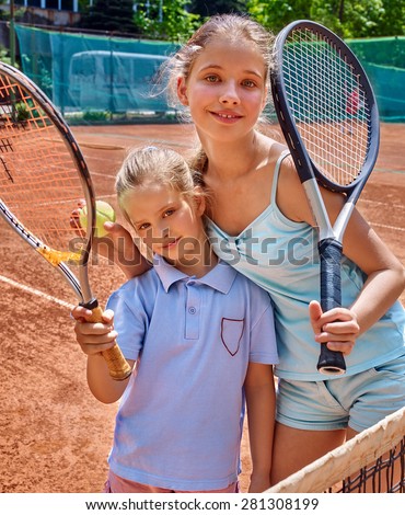 Two sport kids girl with racket and ball on  brown tennis court.